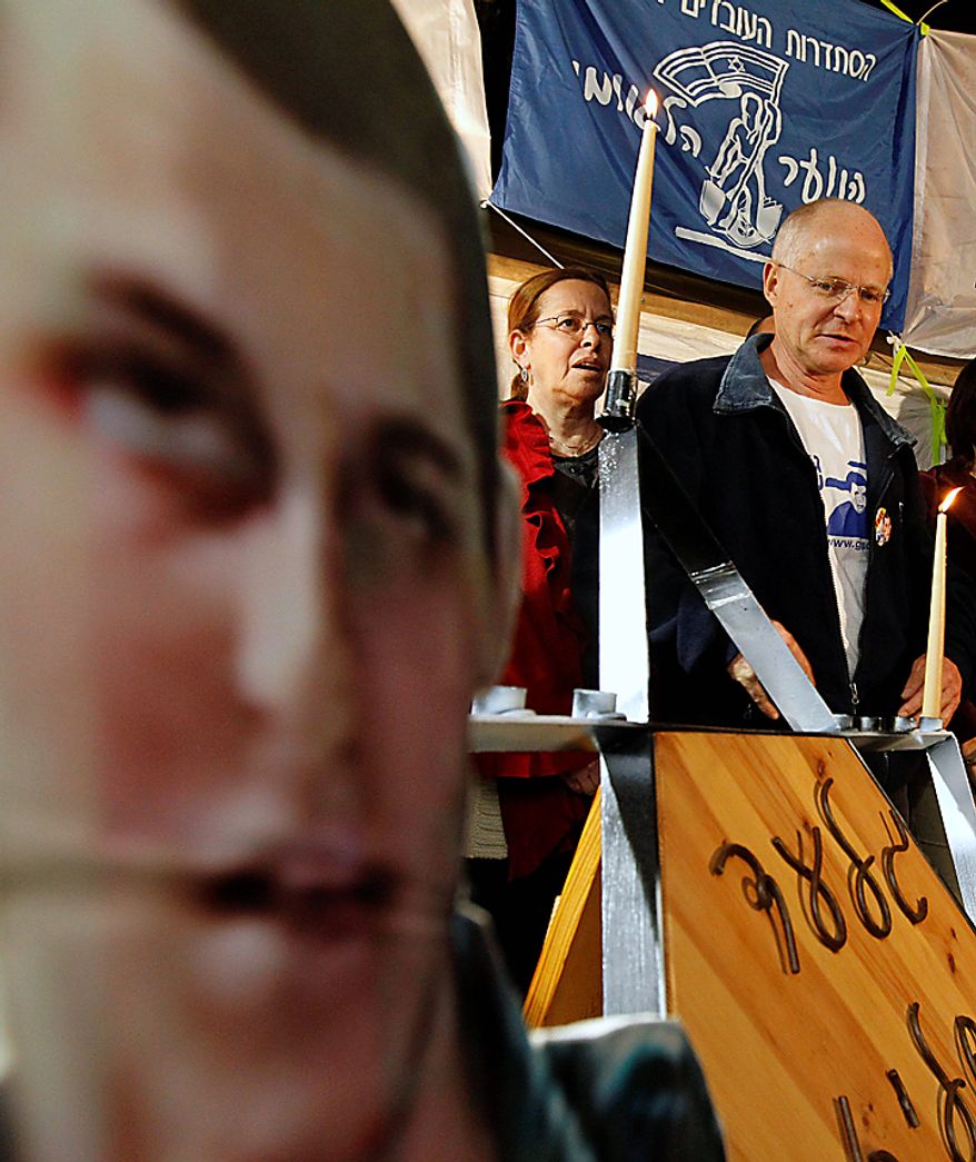 Aviva Schalit, center, and Noam Schalit, stand near a life-sized cutout of their son, captured Israeli army soldier Gilad Schalit, as they light a candle on the eve of the first night of Hanukkah, Wednesday, Dec. 1, 2010. The Jewish festival of light, an eight-day commemoration of the Jewish uprising in the second century B.C. against the Greek-Syrian kingdom, which had tried to put statues of Greek gods in the Jewish Temple in Jerusalem, started Wednesday. (AP Photo/Tara Todras-Whitehill)