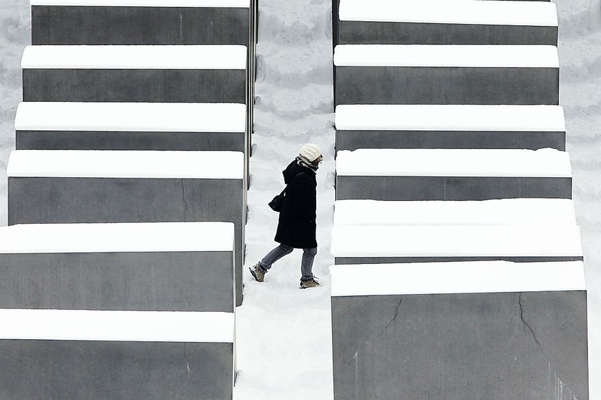 A visitor walks through the snow covered Holocaust Memorial in Berlin on Friday, Dec. 3, 2010. After a day with heavy snow fall cold and cloudy weather is forecast for the German capital. (AP Photo/Markus Schreiber)