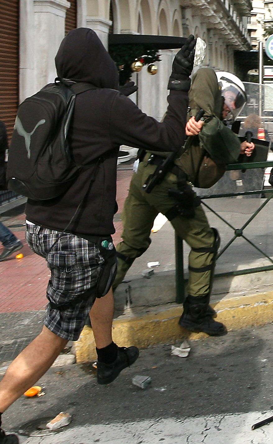 Protester attacks a riot police officer during a rally in Athens on Monday, Dec. 6, 2010. Youths hurled rocks and oranges at a government building in central Athens during a student protest to mark two years since the fatal police shooting of a teenage boy that sparked Greece's worst riots in decades. Police closed roads and deployed several thousand officers around the city but maintained a minimal presence at the site where some 1,500 students gathered outside Athens University's main buildings. (AP Photo/Alkis Konstantinidis)