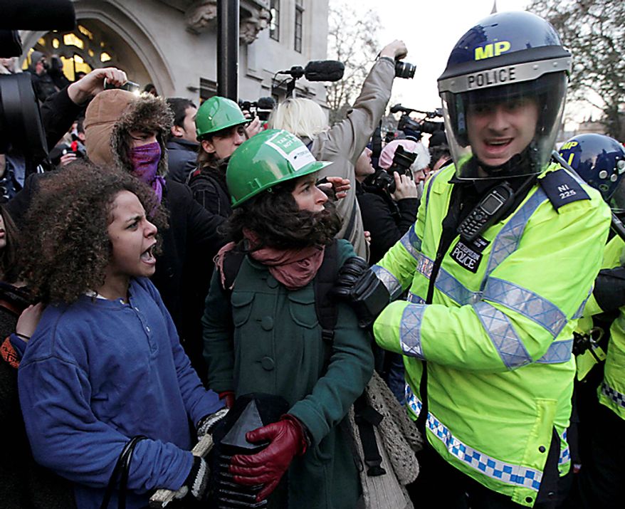 A police officer pushes a protester during a protest against an increase in tuition fees on the edge of Parliament Square in London, Thursday, Dec. 9, 2010. Police clashed with protesters marching to London's Parliament Square as lawmakers debated a controversial plan to triple university tuition fees in England. (AP Photo/Matt Dunham)