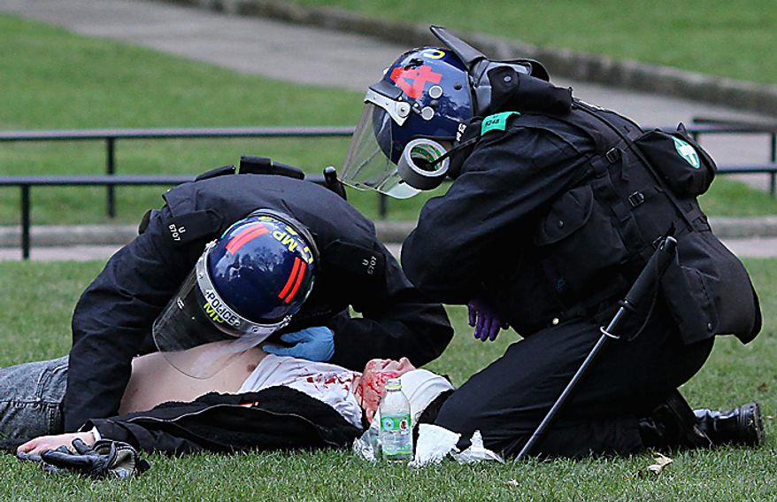 Police officers tend to an injured man outside the Houses of Parliament in London, Thursday Dec. 9, 2010, as police clashed with protesters marching to London's Parliament Square, while lawmakers debated a controversial plan to triple university tuition fees in England.(AP Photo/Gareth Fuller-pa)