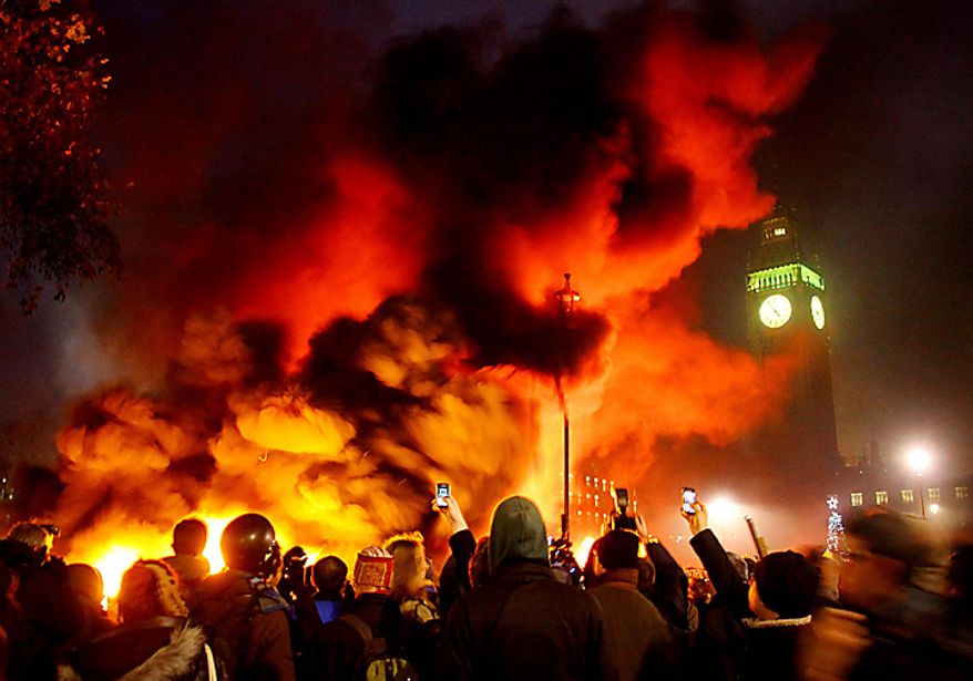 A fire burns in Parliament Square, Westminster, London, as students demonstrate against planned tuition fee increases Thursday Dec. 9, 2010. Police with riot shields and batons pushed angry student protesters away from London's Parliament Square on Thursday as lawmakers debated a controversial plan to triple university tuition fees in England. (AP Photo/Gareth Fuller/PA)