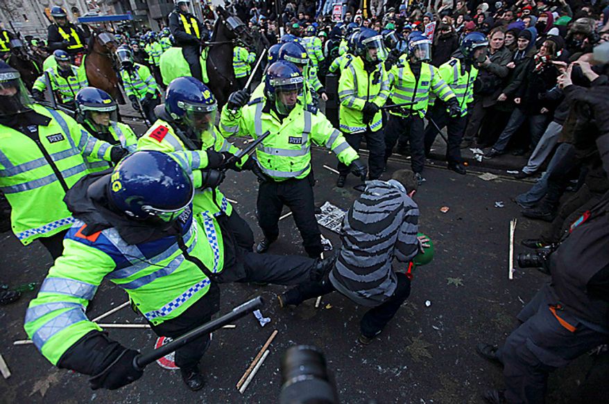 A police officer kicks a demonstrator during a protest against an increase in tuition fees on the edge of Parliament Square in London, Thursday, Dec. 9, 2010. Police clashed with protesters marching to London's Parliament Square as lawmakers debated a controversial plan to triple university tuition fees in England. (AP Photo/Matt Dunham)