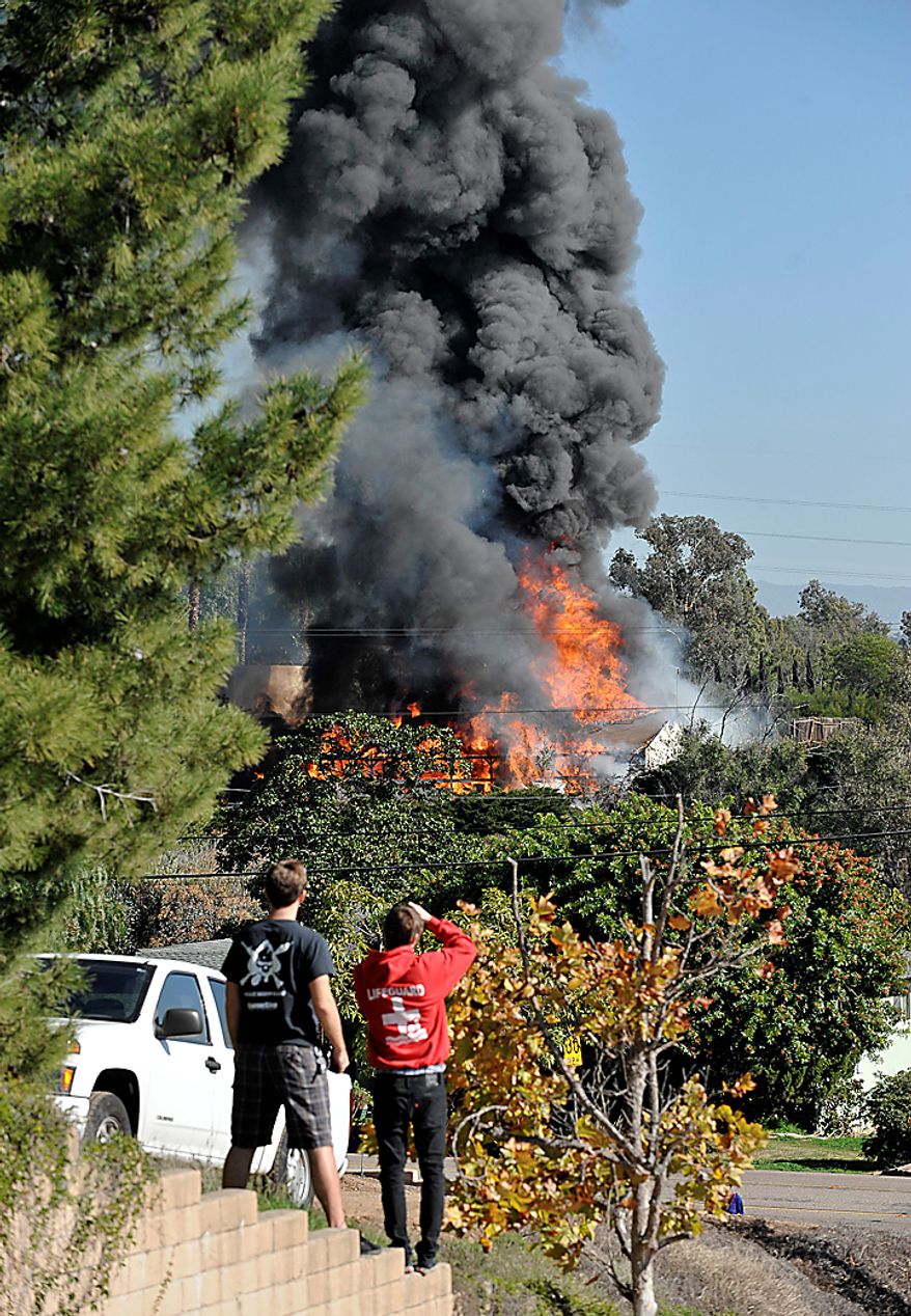 Neighbors watch a house enveloped in flames on Thursday, Dec. 9, 2010 during the controlled burn of the home in Escondido, Calif., that was so packed with homemade explosives that authorities claim they had no choice but to burn it to the ground. The house was rented by an out-of-work software consultant who allegedly assembled an astonishing quantity of bomb-making materials that included chemicals used by Middle Eastern suicide bombers. (AP Photo/Denis Poroy)