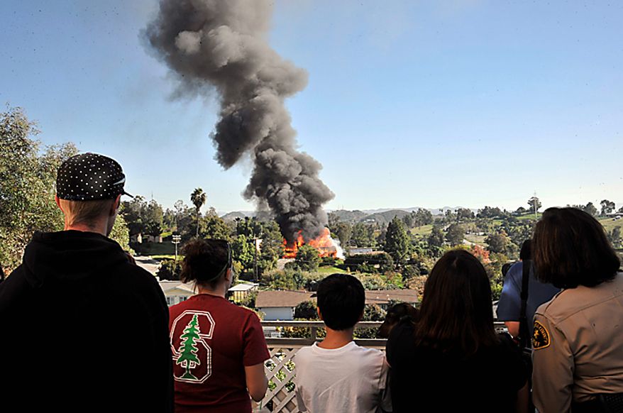 Neighbors look on as a erupts in flames on Thursday, Dec. 9, 2010 during the controlled burn of a home in Escondido, Calif., that was so packed with homemade explosives that authorities claim they had no choice but to burn it to the ground. The house was rented by an out-of-work software consultant who allegedly assembled an astonishing quantity of bomb-making materials that included chemicals used by Middle Eastern suicide bombers. (AP Photo/Denis Poroy)