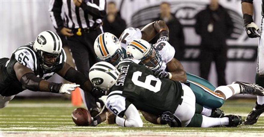 New York Jets quarterback Mark Sanchez (6) fumbles the ball as he is hit by Miami Dolphins linebacker Cameron Wake (91) during the second quarter of an NFL football game at New Meadowlands Stadium, Sunday, Dec. 12, 2010, in East Rutherford, N.J. The Jets recovered the fumble. (AP Photo/Bill Kostroun)