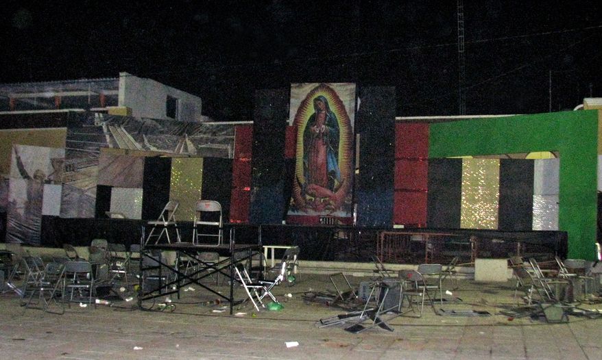 A large image of the Virgin of Guadalupe looms over the plaza where rival gangs held a gunbattle in Tecalitlan, in Mexico's Jalisco state, late Friday, Dec. 10, 2010. At least 11 people were killed, the Jalisco state attorney general's office said. (AP Photo/Raul Aguilar)