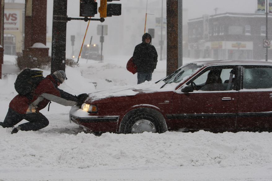 A good Samaritan tries to help free a woman's car from the snow as a winter storm hits St. Paul, Minn., on Saturday, Dec. 11, 2010. (AP Photo/Ann Heisenfelt)