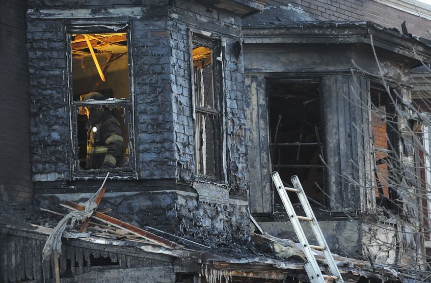 Firefighters investigate the scene of an early-morning, two-alarm fire in Baltimore on Tuesday. Three children were among the six people killed as flames engulfed their row house. (Baltimore Sun via Associated Press)