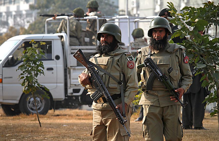 Paramilitary soldiers stand guard near the the Muharram procession in Islamabad, Pakistan, on Thursday, Dec. 16, 2010. Muharram is observed around the world for ten days as mourning in remembrance of the martyrdom of Imam Hussein, the grandson of Prophet Muhammad. (AP Photo/Anjum Naveed)