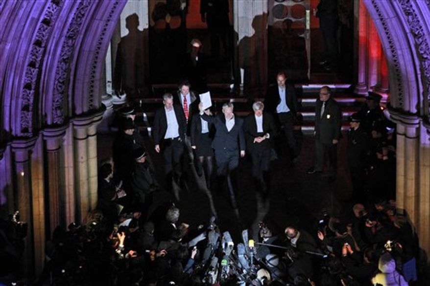The founder of WikiLeaks Julian Assange, center, holds up a court document before addresses the media outside the High Court in London, Thursday, Dec. 16, 2010. Assange is swapping a Victorian prison cell for an English country mansion after a judge granted bail to the WikiLeaks founder wanted in Sweden for questioning on sex-crimes allegations. (AP Photo/Matt Dunham)
