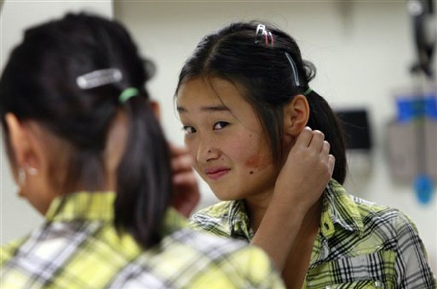 In this Wednesday, Nov. 24, 2010, photo Elise Lutz looks into a mirror and admires her new prosthetic ear at the Anaplastology Clinic in Durham, N.C. (AP Photo/Gerry Broome)