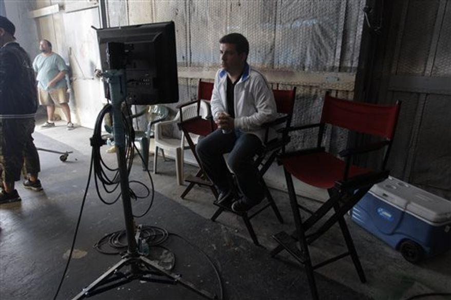 In this Oct. 10, 2010 photo, David Rousseau, stands in a Miami sound stage as Pit Bull records a music video. As a child, music video director Rousseau lived in Miami's Little Havana neighborhood and would listen to the songs wafting from the nearby Orange Bowl. It was the 1980s and all the biggest acts played there: Pink Floyd, Genesis, Bruce Springsteen and Michael Jackson. It made him envision what the music would look like. Today, Rousseau, 35, has directed videos for some of music's biggest acts: Lil Wayne, Enrique Iglesias, Pitbull, and T-Pain. He is known for bright colors and graphics that complement the high-energy music he's showcasing. (AP Photo/J Pat Carter)