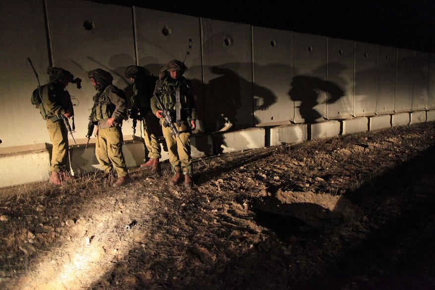 ** FILE ** Israeli soldiers in southern Israel near the Israel-Gaza border examine a crater created by a rocket fired by Palestinian militants from the Gaza Strip on Thursday, Dec. 9, 2010. (AP Photo/Tsafrir Abayov)