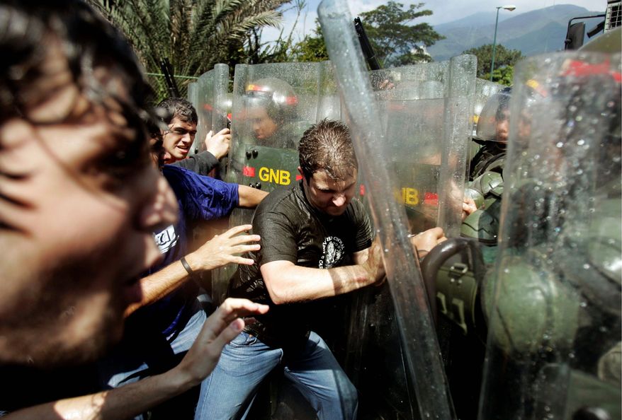 Associated Press photographs
Demonstrators clash with soldiers Thursday outside the Central University of Venezuela in Caracas. Students protested against a law that increases government powers over the country's universities.