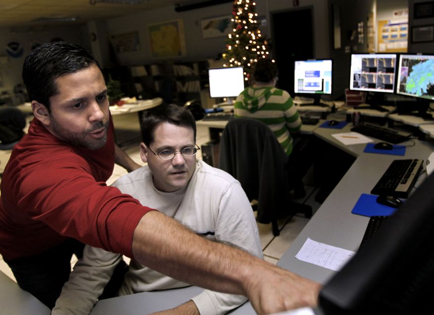Brandon Locklear (left) and Jeff Orrock, meteorologists with the National Weather Service in Raleigh, N.C., track the snowstorm moving into the Triangle area on Saturday evening, Dec. 25, 2010. (AP Photo/The News & Observer, Takaaki Iwabu)