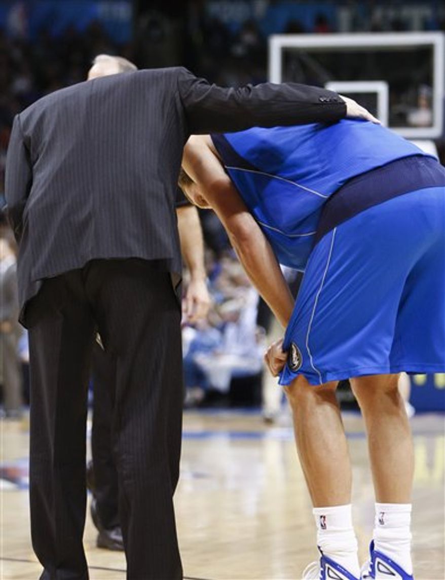 Dallas Mavericks forward Dirk Nowitzki, right, stands with a trainer after getting hurt during the second quarter of an NBA basketball game against the Oklahoma City Thunder in Oklahoma City, Monday, Dec. 27, 2010. (AP Photo/Alonzo Adams)