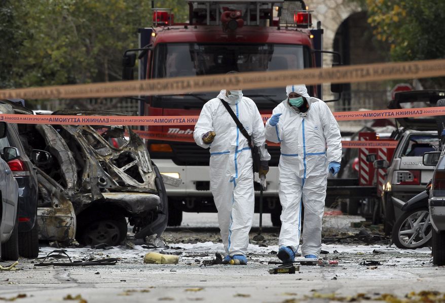 Police forensic experts gather evidence at the scene of a motorcycle bomb blast that damaged two court administration buildings in Athens on Thursday, Dec. 30, 2010. No injuries were reported. (AP Photo/Petros Giannakouris)