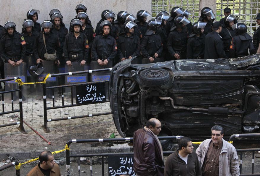 Egyptian riot police form a line behind an upturned and burnt car outside the Coptic Christian Saints Church, unseen, in the Mediterranean port city of Alexandria, Egypt, on Saturday, Jan. 1, 2011. A car exploded in front of the church early Saturday as worshippers emerged from a New Year's Mass, killing at least 21 people according to officials. (AP Photo/Ben Curtis)