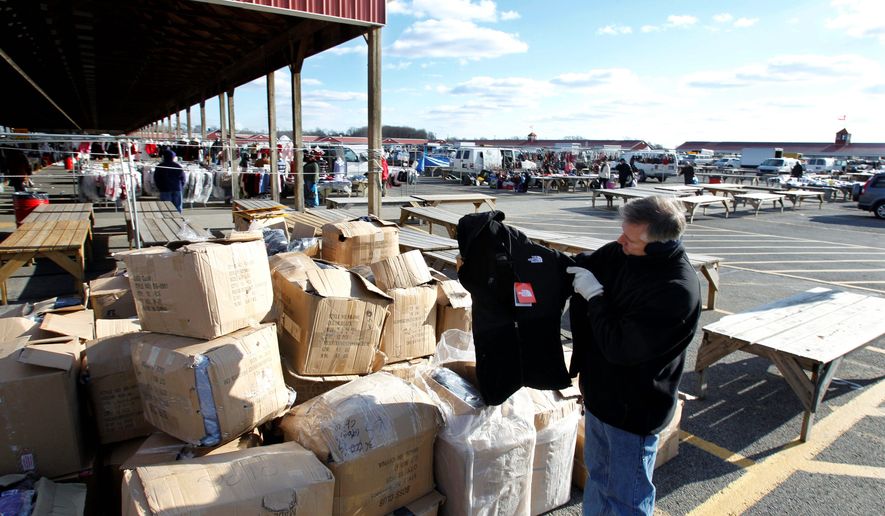 New Jersey State Police Lt. Michael E. McDonnell finds a counterfeit North Face coat among boxes full of fake name-brand clothing that police seized last month from a vendor at a flea market. (Associated Press)
