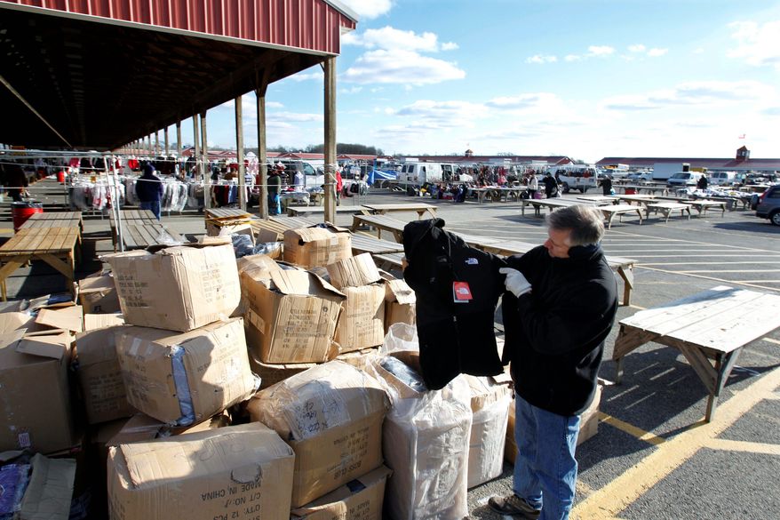 New Jersey State Police Lt. Michael E. McDonnell finds a counterfeit North Face coat among boxes full of fake name-brand clothing that police seized last month from a vendor at a flea market. (Associated Press)