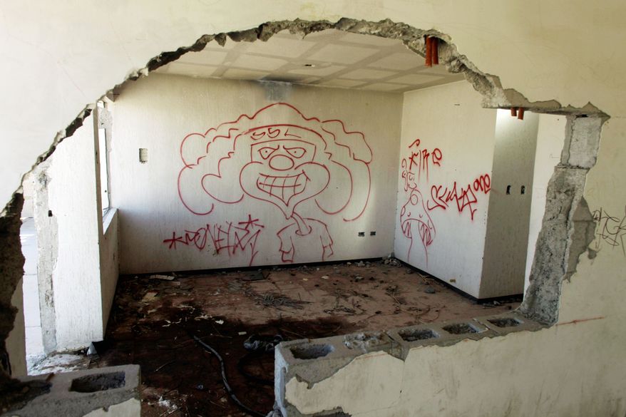 Graffiti covers the shell of a home in a nearly abandoned working-class neighborhood. No one knows how many have fled the city. (Associated Press)