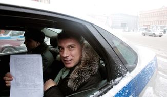 UNDER ARREST: Russian opposition leader Boris Nemtsov displays a protocol paper as he is escorted to court in Moscow. (Associated Press)