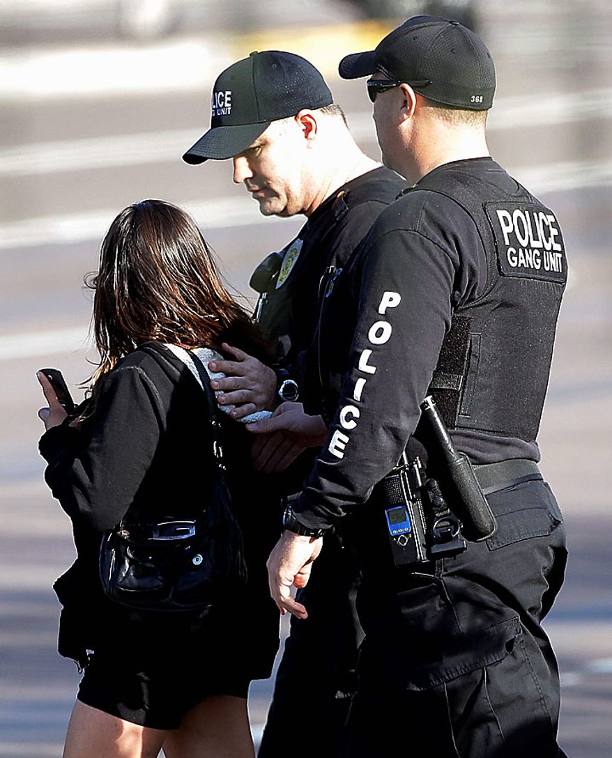 Law enforcement officials escort a lady to a police car outside a Baja Fresh restaurant Wednesday, Jan. 5, 2011 in Chandler, Ariz. Chandler police spokesman Sgt. Joe Favazzo says a gunman entered a Baja Fresh restaurant and fired a gun in what police think was a warning to customers following a shooting at the Chandler Mall. (AP Photo/Matt York)