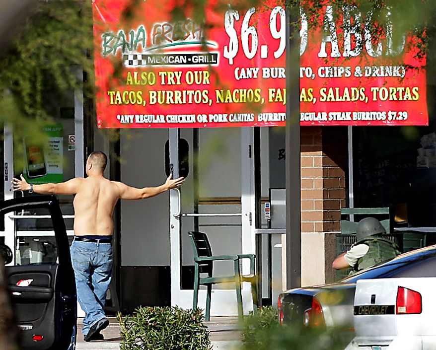 A man comes out of a Baja Fresh restaurant with his hands up Wednesday, Jan. 5, 2011 in Chandler, Ariz. Chandler police spokesman Sgt. Joe Favazzo says a gunman entered a Baja Fresh restaurant and fired a gun in what police think was a warning to customers following a shooting at the Chandler Mall. (AP Photo/Matt York)
