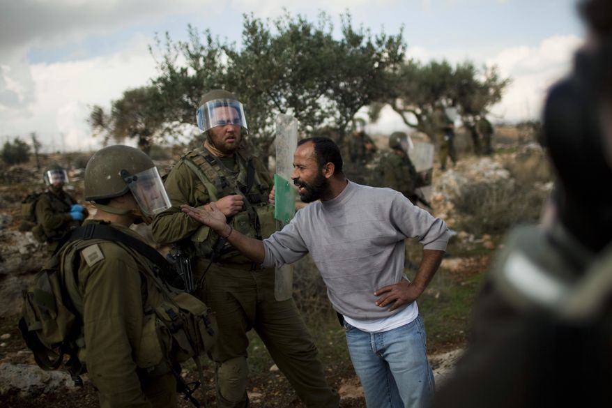 A Palestinian man argues with Israeli soldier during a protest against Israel's separation barrier in the West Bank village of Bilin near Ramallah, Friday, Jan 7, 2011. Some held banners with photographs of Jawaher Abu Rahmeh, a 36-year-old villager who collapsed at last week's protest and died the next day. Palestinian doctors who treated Ms. Abu Rahmeh said she collapsed after inhaling tear gas fired by Israeli troops and died as a result of the gas. (AP Photo/Bernat Armangue)
