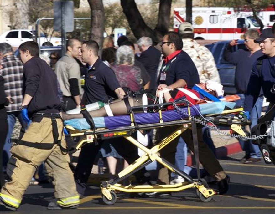 Emergency personnel and Daniel Hernandez, an intern for U.S. Rep. Gabrielle Giffords, second right, move Giffords after she was shot in the head outside a shopping center in Tucson, Ariz. on Saturday, Jan. 8, 2011. (AP Photo/James Palka)