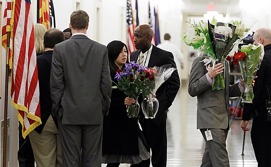 Congressional staffers bring flowers out of the office of Rep. Gabrielle Giffords, Arizona Democrat, in the Longworth House Office Building on Capitol Hill in Washington, Monday, Jan. 10, 2011. Mrs. Giffords was shot Saturday in a Tucson shooting rampage that left six people dead. (AP Photo/Charles Dharapak)