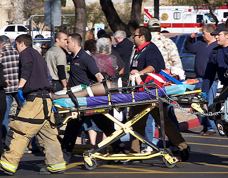 Emergency personnel and Daniel Hernandez, an intern for U.S. Rep. Gabrielle Giffords, second right, move Mrs. Giffords after she was shot in the head outside a shopping center in Tucson, Ariz. on Saturday, Jan. 8, 2011. (AP Photo/James Palka)