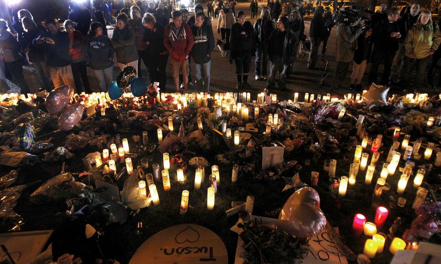 Dozens gather at a makeshift memorial in front of the University Medical Center in Tucson, Ariz., on Monday, Jan. 10, 2011. The memorial was set up for Rep. Gabrielle Giffords, who is still in critical condition at the hospital, and other victims who were shot on Saturday. (AP Photo/Ross D. Franklin)