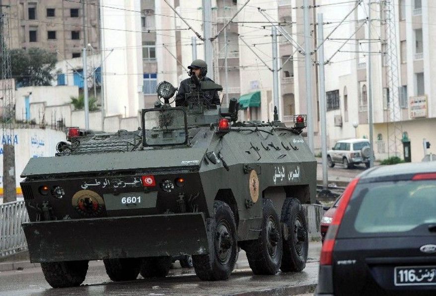 A soldier drives an armored vehicle through Ettadhamoun on Wednesday. Riots were reported late Tuesday in the Ettadhamoun neighborhood three miles from Tunis, the first time the violence has reached so near the capital. Tunisia's prime minister said Wednesday the country's interior minister has been fired after deadly protests over unemployment and he also announced that most prisoners arrested during nearly a month of riots are being freed. (Associated Press)