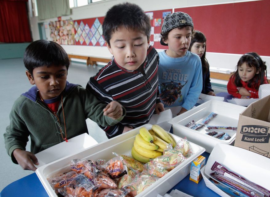 Second-grader Jonathan Cheng (center) looks over fruits and vegetables in the cafeteria at Fairmeadow Elementary School in Palo Alto, Calif. School lunch rules proposed by the U.S. Agriculture Department would limit calories allowed in school meals while increasing whole grains, fruits and vegetables. (Associated Press)