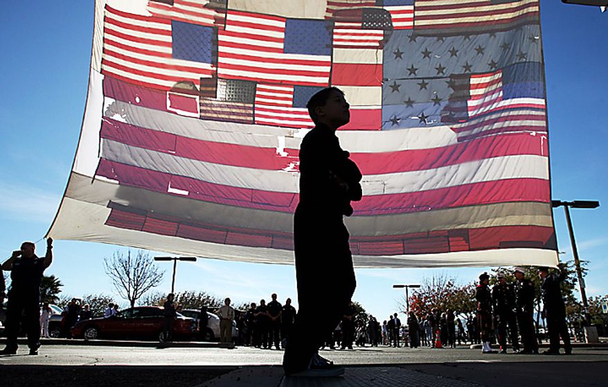 A boy walks past a large American flag recovered from ground zero after the 9/11 attacks, outside the entrance at the St. Elizabeth Ann Seton Church for the funeral of 9-year-old Christina Taylor Green Thursday, Jan. 13, 2011, in Tucson, Ariz. Green, the youngest victim of Saturday's shooting in Tucson, was born on the day of the Sept. 11 attacks in 2001. (AP Photo/Mamta Popat, Pool)