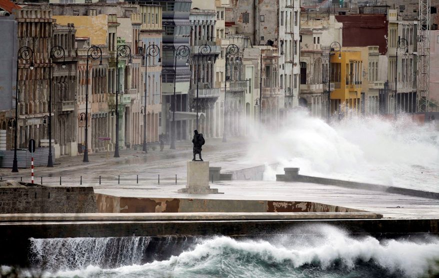 FILE - In this Dec. 13, 2010 file photo, a statue of Venezuelan independence hero Francisco de Miranda stands as waves splash over the sea wall onto Malecon Avenue during heavy winds in Havana, Cuba. Thousands of Cuban-Americans are heading to Havana this holiday season carrying everything from electronics and medicine to clothing and toiletries to help relatives back home supplement monthly salaries averaging about $20. Not only are Cuban-Americans visiting the island in far greater numbers since President Barack Obama lifted travel restrictions last year, they are bringing more stuff. One carrier says the average bag weight per passenger is up 55 percent _ and many Miami-Havana flights are shadowed by a separate cargo plane just to haul the load. (AP Photo/Javier Galeano, File)