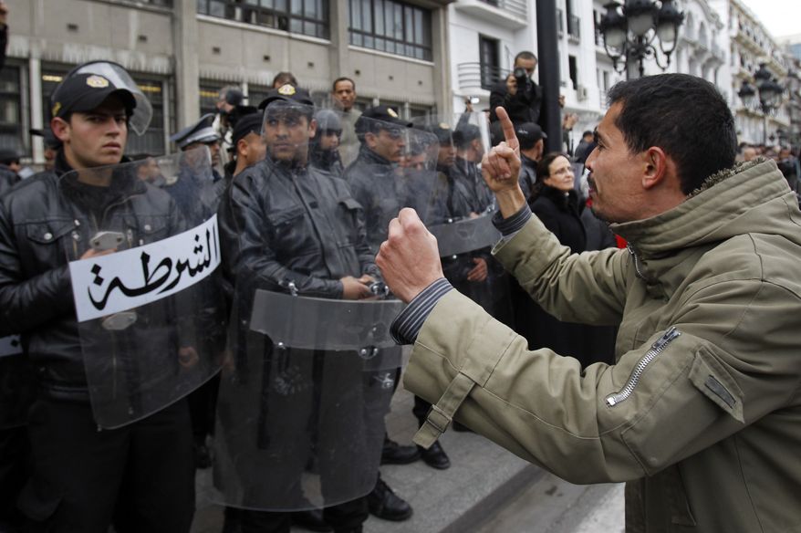 A protester faces police officers as he chants slogans against President Zine El Abidine Ben Ali in Tunis, Friday, Jan. 14, 2011. Thousands of angry demonstrators marched through Tunisia's capital Friday, demanding the resignation of the country's autocratic leader a day after he appeared on TV to try to stop deadly riots that have swept the North African nation. (AP Photo/Christophe Ena)