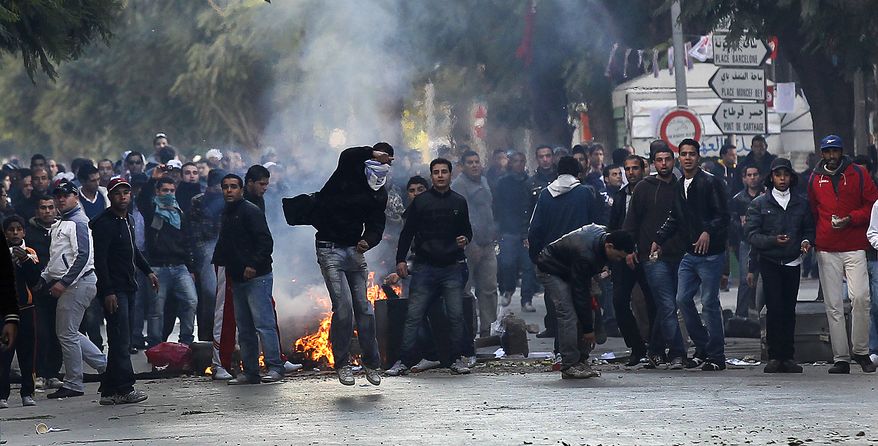 Demontrators throw rocks towards police during clashes in Tunis, Friday, Jan. 14, 2011. Tunisia's president declared a state of emergency and announced that he would fire his government as violent protests escalated Friday, with gunfire echoing in the North African country's usually calm capital and police lobbing tear gas at protesters. (AP Photo/Christophe Ena)