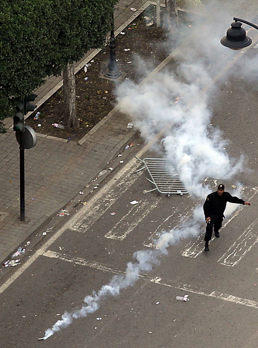 A police officer uses teargas during clashes in Tunis, Friday, Jan. 14, 2011. Tunisia's president declared a state of emergency and announced that he would fire his government as violent protests escalated Friday, with gunfire echoing in the North African country's usually calm capital and police lobbing tear gas at protesters. (AP Photo/Christophe Ena)