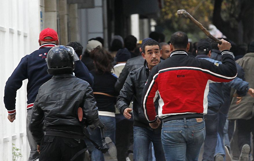 Plain clothed police and riot police officers clash with demonstrators in Tunis, Friday, Jan. 14, 2011. Tunisia's president declared a state of emergency and announced that he would fire his government as violent protests escalated Friday, with gunfire echoing in the North African country's usually calm capital and police lobbing tear gas at protesters. (AP Photo/Christophe Ena)