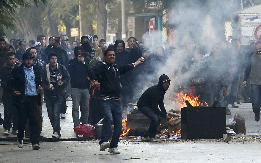 Demonstrators throws stones at police during clashes in Tunis, Friday, Jan. 14, 2011. Tunisia's president declared a state of emergency and announced that he would fire his government as violent protests escalated Friday, with gunfire echoing in the North African country's usually calm capital and police lobbing tear gas at protesters. (AP Photo/Christophe Ena)