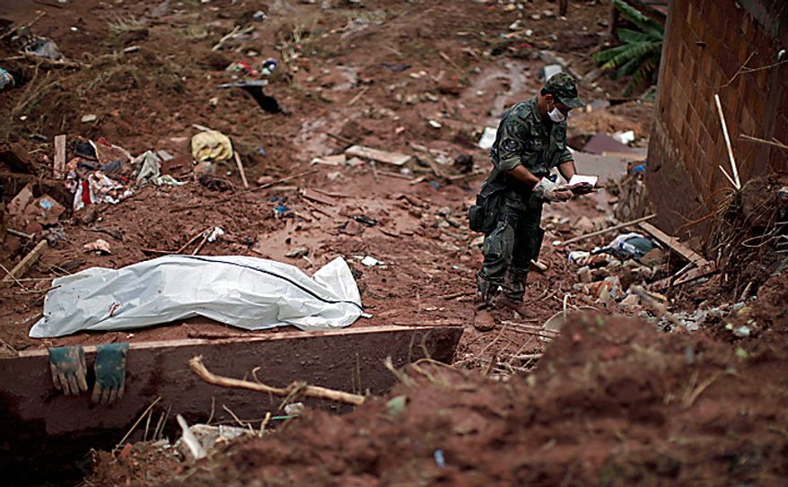 A rescue worker checks a notebook found next to the recovered body of landslide victim Samara Coelho da Silva, 13, left, inside a body bag, in Nova Friburgo, Brazil, Monday, Jan. 17, 2011. Brazil's army on Monday sent 700 soldiers to help throw a lifeline to desperate neighborhoods that have been cut off from food, water or help in recovering bodies since mudslides killed at least 642 people. (AP Photo/Felipe Dana)