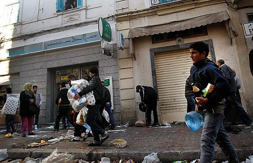 People take food and other goods from a destroyed store in Tunis, Saturday, Jan. 15. 2011. Unrest engulfed Tunisia on Saturday after a popular rebellion forced the president to flee. Dozens of inmates were killed in two prison fires, looters emptied shops and torched the main train station and gunfire echoed through the capital. (AP Photo/Christophe Ena)