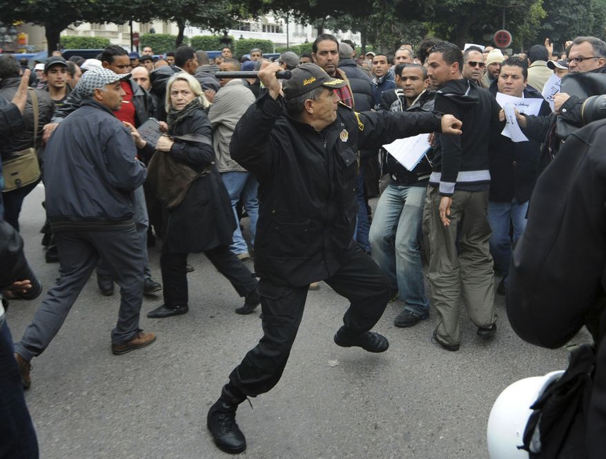 A police officer faces protesters during a demonstration against the Constitutional Democratic Rally, RCD, party of ousted President Zine El Abidine Ben Ali in the center of Tunis, Tuesday, Jan. 18. 2011. (AP Photo/Salah Habibi)