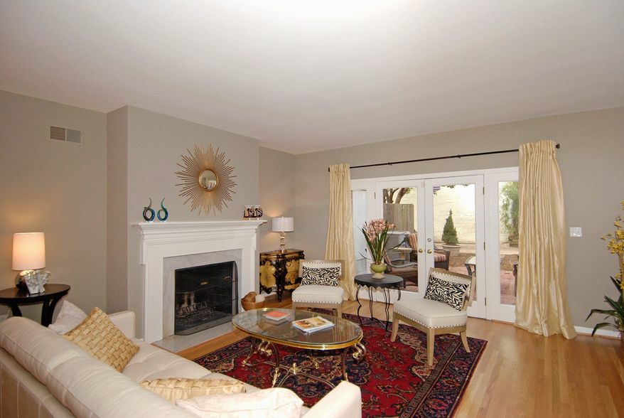 The living room features a wood-burning fireplace with a marble hearth and French doors leading to the patio.