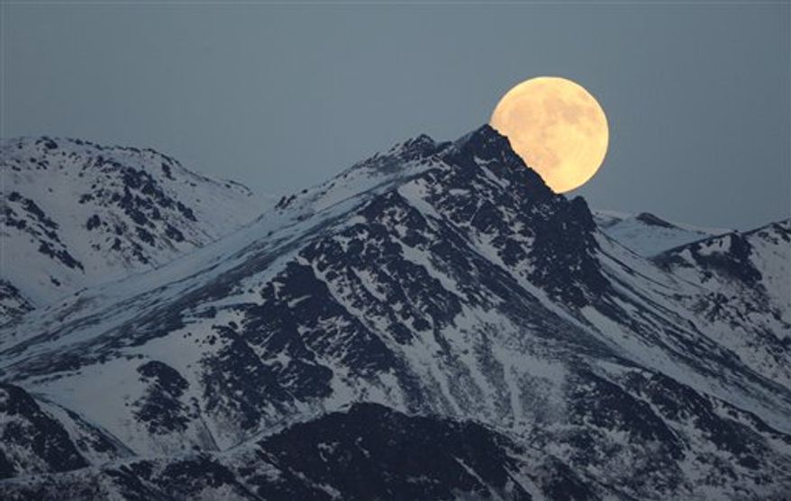 The moon rises above a mountain range in Alaska on Tuesday, Jan. 18, 2011. (AP PHOTO/BILL ROTH/Anchorage Daily News)