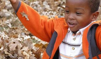 Ross Haskell&#x27;s adopted son, Alexander Griffith-Haskell, plays in the autumn leaves outside the family&#x27;s home in Wichita, Kan. For the most part, the Haitian orphans are thriving after a year with American families. (Ross Haskell via Associated Press)