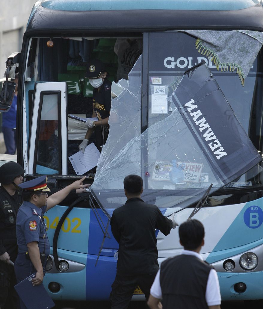 Philippine National Police investigators gathers evidence on a damaged passenger bus following an explosion at the financial district of Makati, Philippines on Tuesday Jan. 25, 2011. The powerful explosion ripped through the air-conditioned bus Tuesday killing several people and wounding more than a dozen others. (AP Photo/Aaron Favila)